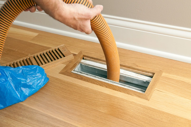A person vacuuming , focusing on cleaning the Air Duct.